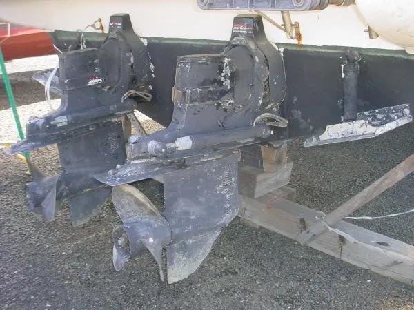 Slide: The Image of 1998 Maxum 3000SCR boat outdrives on dry dock, showing wear and marine growth. - 16