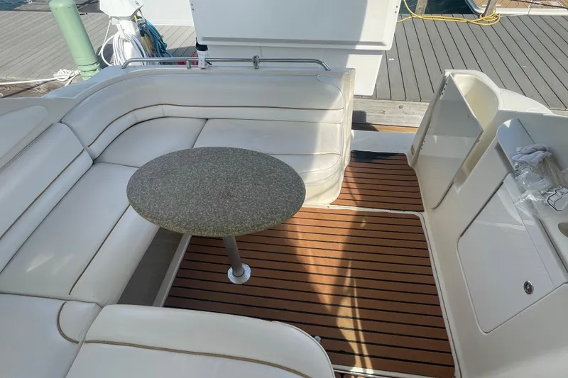 Slide: The Image of 1998 Maxum 3000SCR boat interior with white seating and round table on wooden deck. - 28