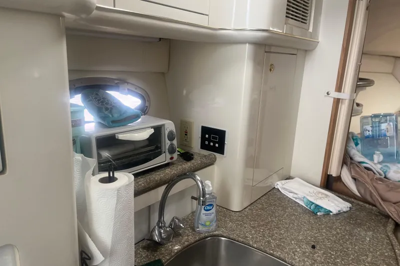 Slide: The Image of 1998 Maxum 3000SCR boat interior with kitchenette, featuring sink, toaster oven, and storage. - 54