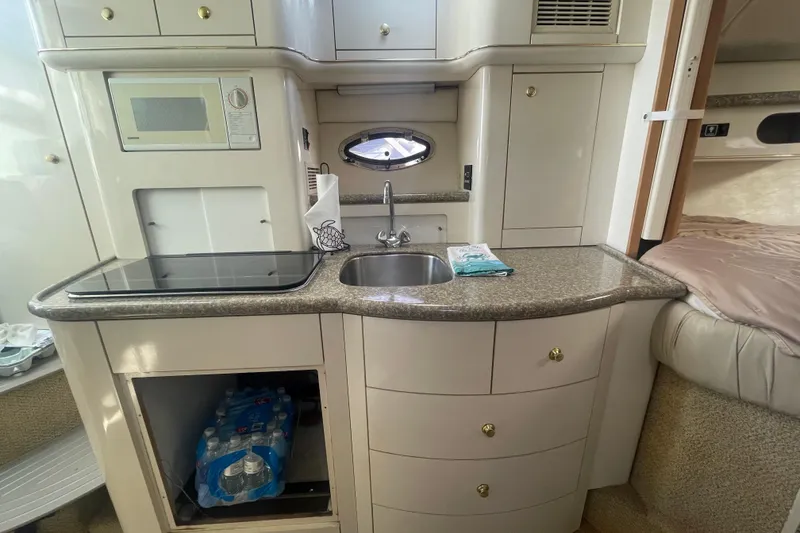 Slide: The Image of 1998 Maxum 3000SCR boat interior kitchen with sink, microwave, and storage cabinets. - 70