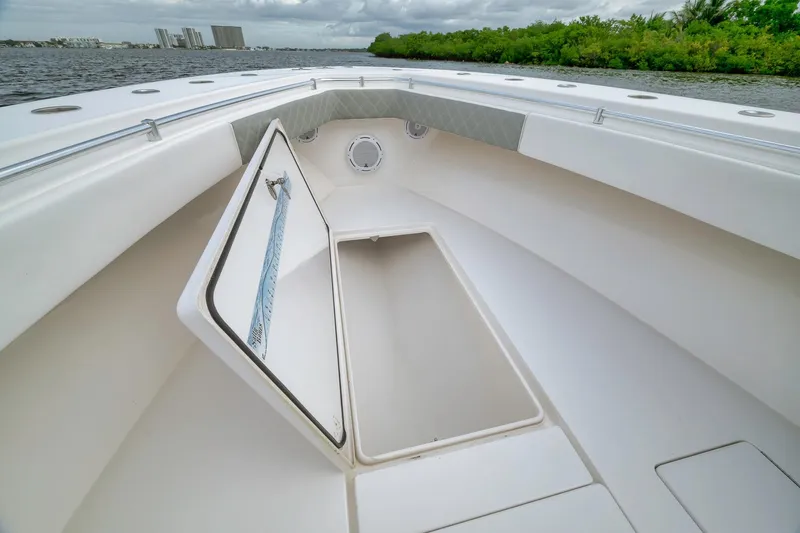 Slide: The Image of 2012 Contender 32 Tournament boat with open storage compartment, docked by lush greenery. - 37