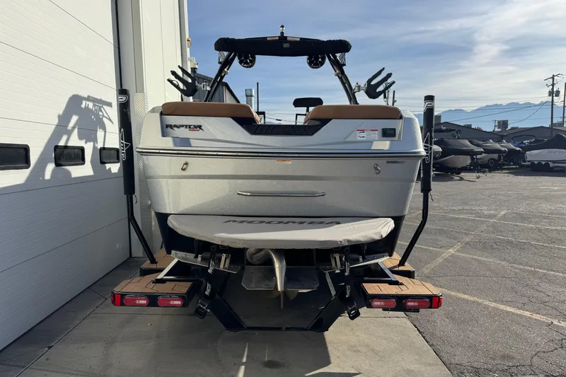 Slide: The Image of 2024 Moomba Tykon boat rear view, parked outdoors near a building. - 2