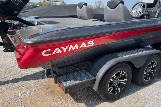 Slide: The Image of 2022 Caymas CX19 boat on trailer, red and black design, dual axles, outdoor setting. - 2