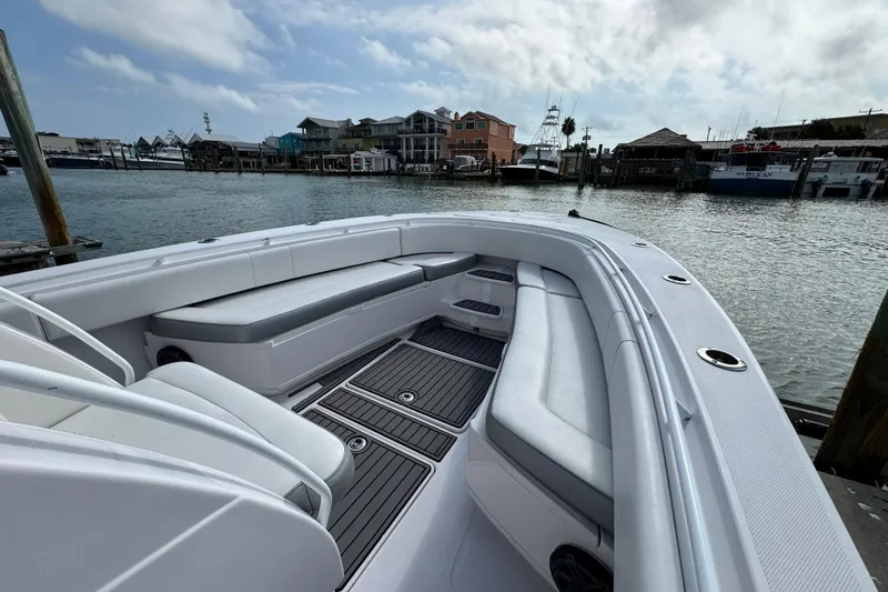 Slide: The Image of 2018 Fountain 34 Center Console boat with spacious seating, docked at a marina. - 18