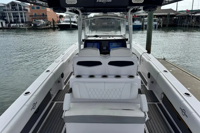 Slide: The Image of 2018 Fountain 34 Center Console boat docked at marina, featuring spacious seating and modern controls. - 24