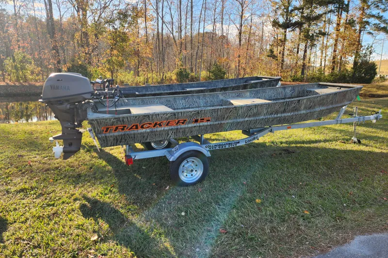 The Image of 2026 Tracker Grizzly 15 Jon boat on trailer, parked on grass near trees. - 0