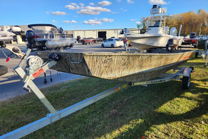 Slide: The Image of 2026 Tracker Grizzly 15 Jon boat on Load Rite trailer, parked outdoors under blue sky. - 2