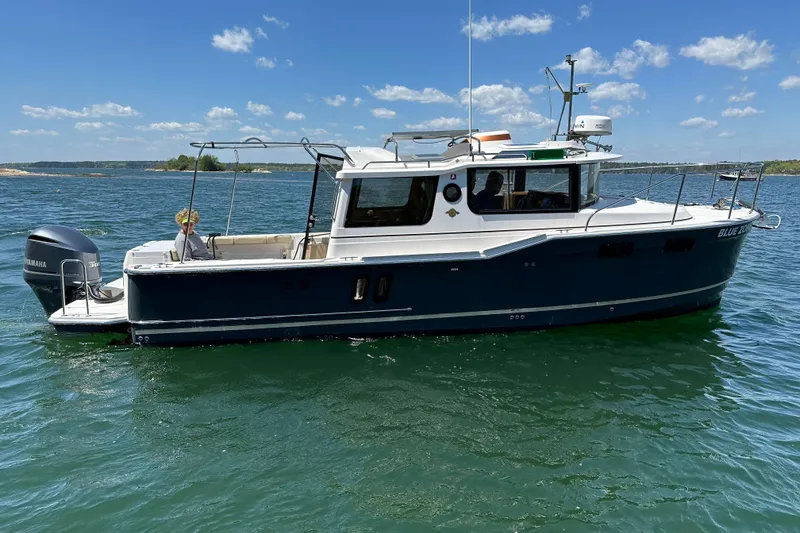 The Image of 2020 Ranger Tugs R-27 Luxury Edition Tug on calm water under blue sky. - 0