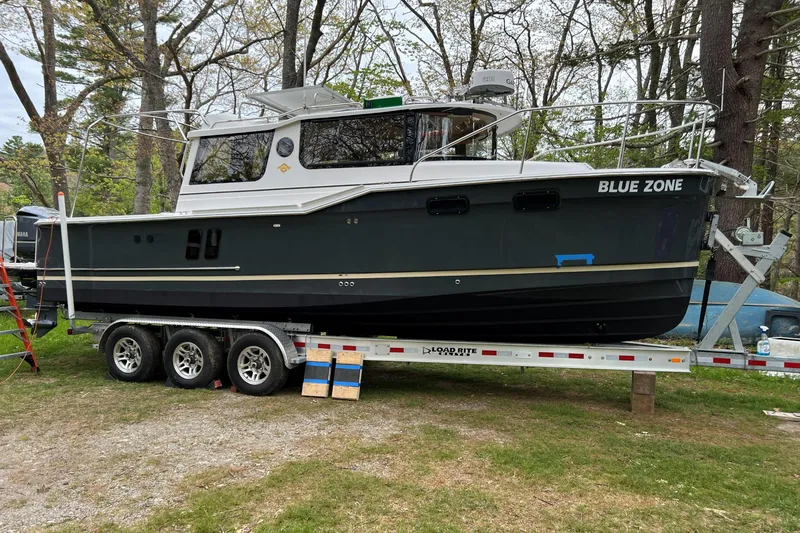 Slide: The Image of 2020 Ranger Tugs R-27 Luxury Edition Tug on trailer, named "Blue Zone," in wooded area. - 28