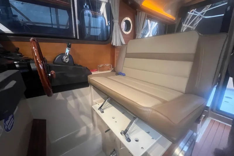 Slide: The Image of 2020 Ranger Tugs R-27 Luxury Edition Tug interior with beige seating and wooden steering wheel. - 9