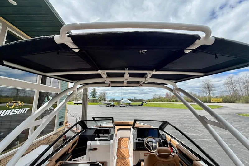 Slide: The Image of 2026 Cobalt R8 Outboard boat interior with canopy, parked near a showroom. - 31
