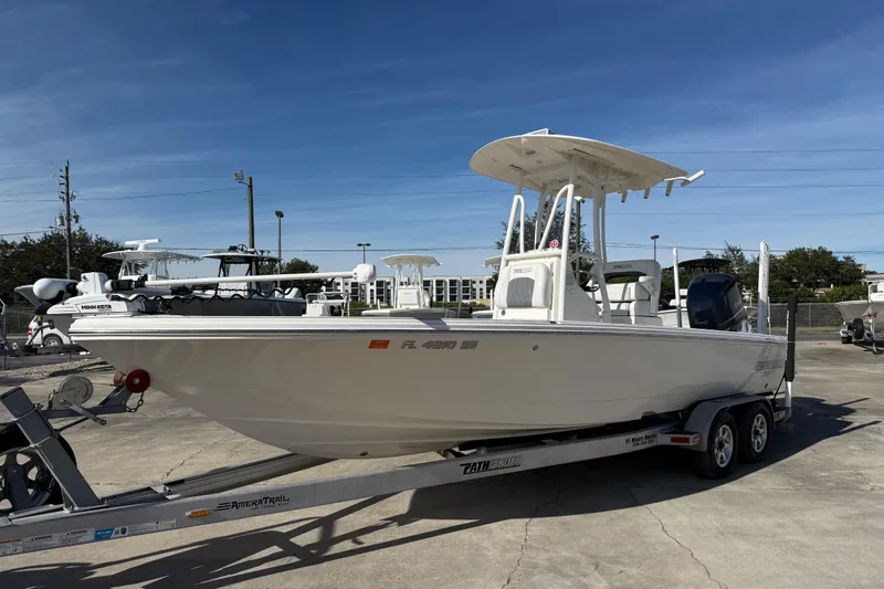 Slide: The Image of 2021 Pathfinder 2500 Hybrid boat on trailer, parked outdoors under clear blue sky. - 21