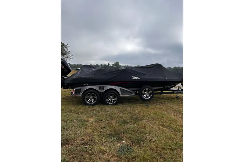Slide: The Image of 2023 Ranger Z520R Ranger Cup boat covered on grassy field under cloudy sky. - 1