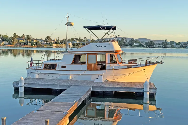 The Image of 1979 CHB Double Cabin Trawler docked on calm water at sunset. - 0