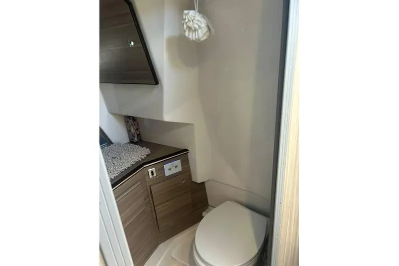 Slide: The Image of Compact bathroom in 2026 Solara S-310 SB boat, featuring modern fixtures and wood cabinetry. - 12