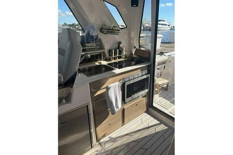 Slide: The Image of Modern kitchen area inside 2026 Solara S-310 SB yacht, featuring sink, microwave, and storage. - 5