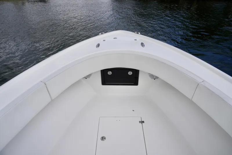 Slide: The Image of 2019 Dusky 33 boat bow with white seating and storage, on calm water. - 17
