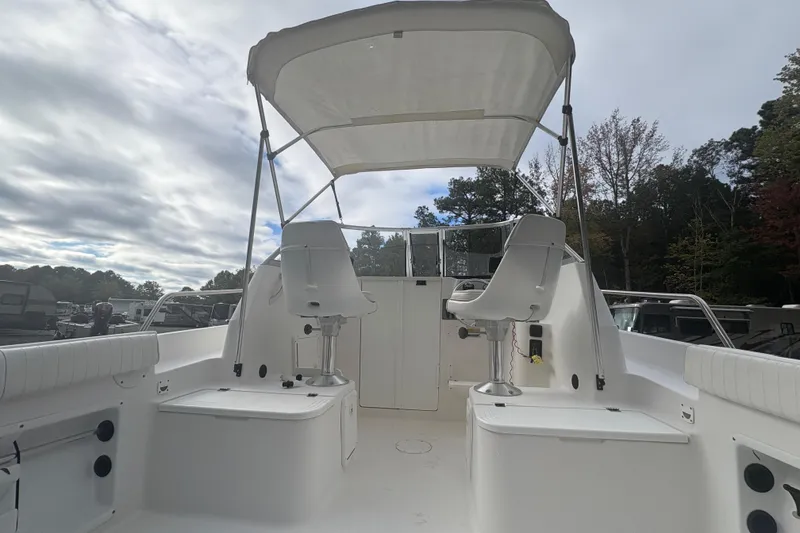 Slide: The Image of 2012 Clearwater 2100 WA boat interior with seating and canopy under cloudy sky. - 16