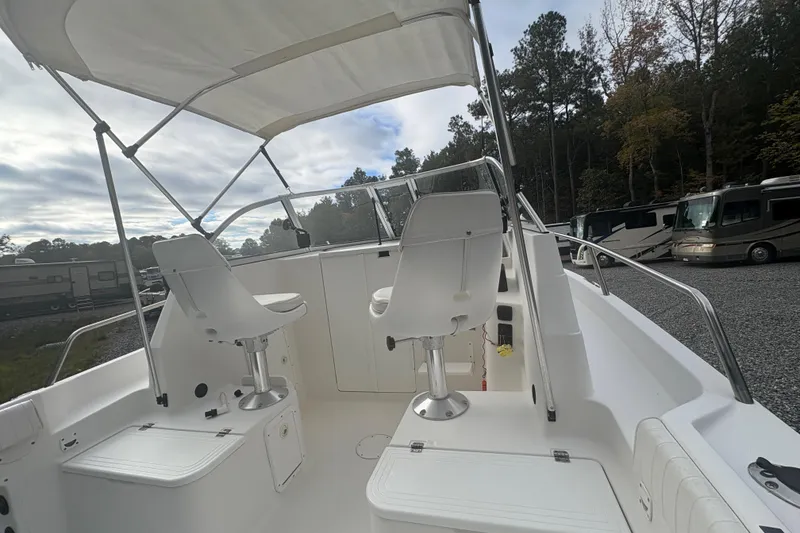 Slide: The Image of 2012 Clearwater 2100 WA boat interior with seating and canopy, parked near RVs. - 9