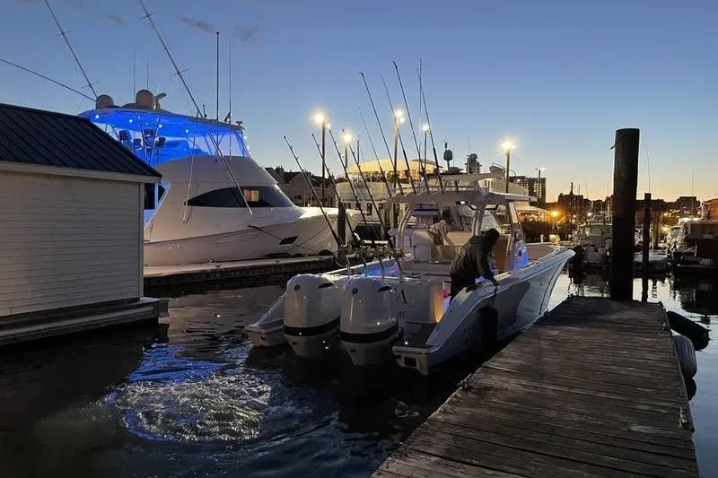 Slide: The Image of 2019 Pursuit S 328 Sport boat docked at marina during twilight, with fishing rods visible. - 8