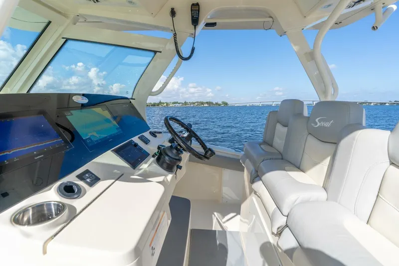 Slide: The Image of 2023 Scout 355 LXF boat interior with modern helm and seating, overlooking serene waters. - 10