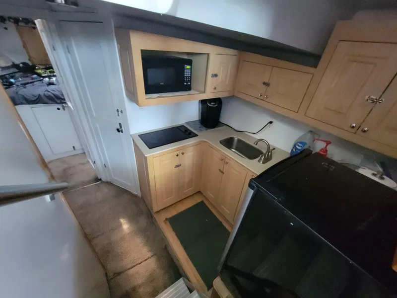 Slide: The Image of Compact kitchen area in a 1998 Custom Carolina 45 Willis Boatworks, featuring wooden cabinets and modern appliances. - 30