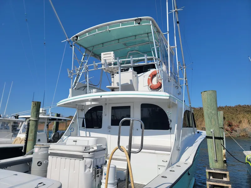 Slide: The Image of 1998 Custom Carolina 45 Willis Boatworks docked, featuring a spacious upper deck and fishing equipment. - 5