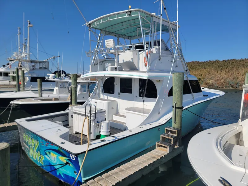 Slide: The Image of 1998 Custom Carolina 45 Willis Boatworks docked, featuring a spacious deck and flybridge. - 8