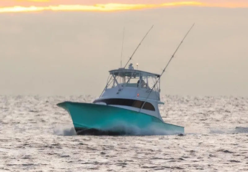 Slide: The Image of Custom Carolina 45 Willis Boatworks 1998 cruising on water at sunset near coastal homes. - 2