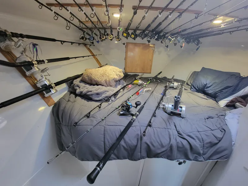Slide: The Image of Interior of 1998 Custom Carolina 45 Willis Boatworks with fishing rods and cozy bedding. - 24