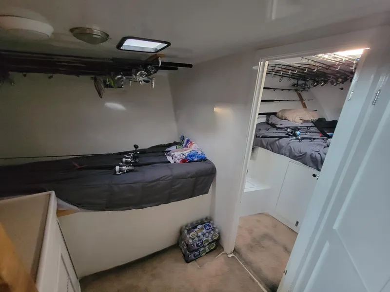 Slide: The Image of Interior of 1998 Custom Carolina 45 Willis Boatworks with fishing rods and cozy sleeping area. - 27