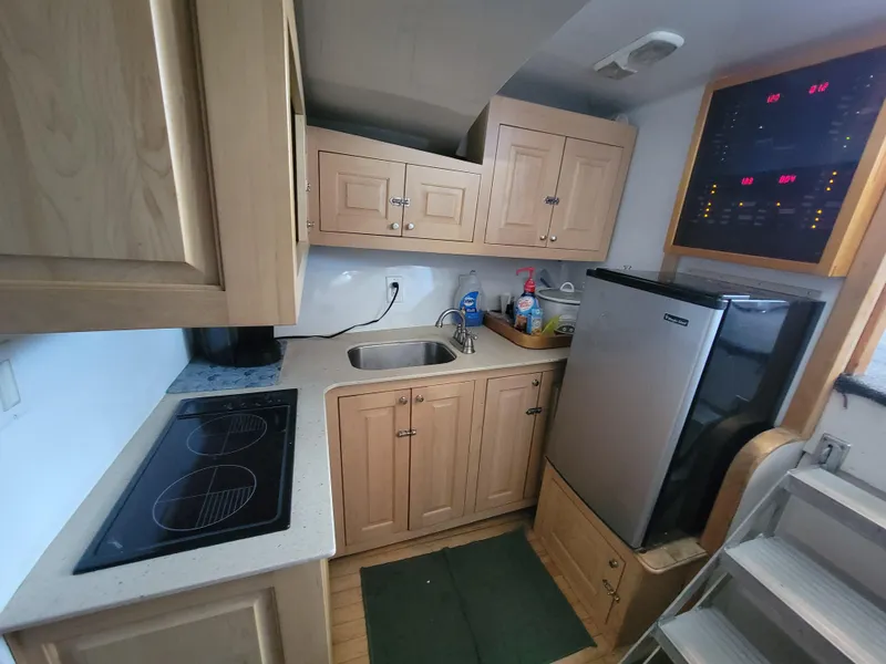Slide: The Image of Compact kitchen in a 1998 Custom Carolina 45 Willis Boatworks, featuring wooden cabinets and modern appliances. - 28