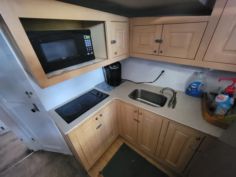 Slide: The Image of Compact kitchen in a 1998 Custom Carolina 45 Willis Boatworks, featuring microwave and sink. - 29