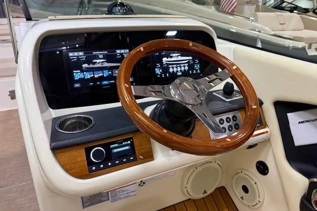 Slide: The Image of 2023 Chris-Craft Calypso 28 dashboard with wooden steering wheel and modern digital displays. - 22
