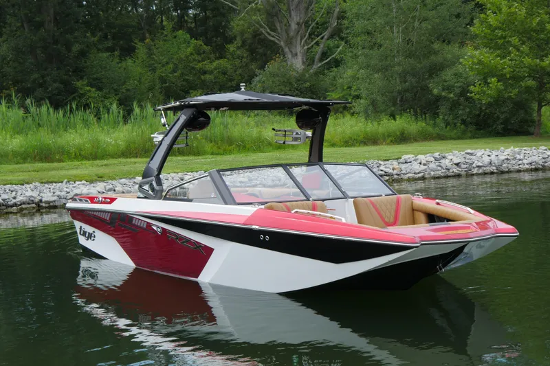 The Image of 2017 Tigé RZX2 boat with red and white design on a calm lake. - 1