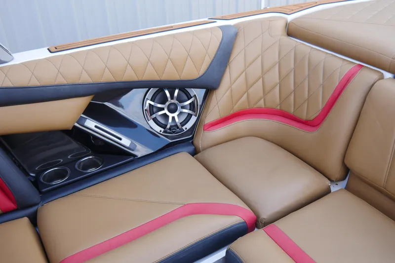 Slide: The Image of 2017 Tigé RZX2 boat interior with tan and red upholstery, speaker, and cup holders. - 11