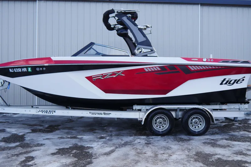 Slide: The Image of 2017 Tigé RZX2 boat on trailer, red and white design, parked outdoors. - 4
