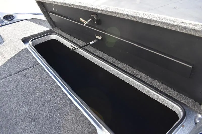 Slide: The Image of Open storage compartment in 2026 Triton 179 TrX boat, featuring carpeted interior. - 14