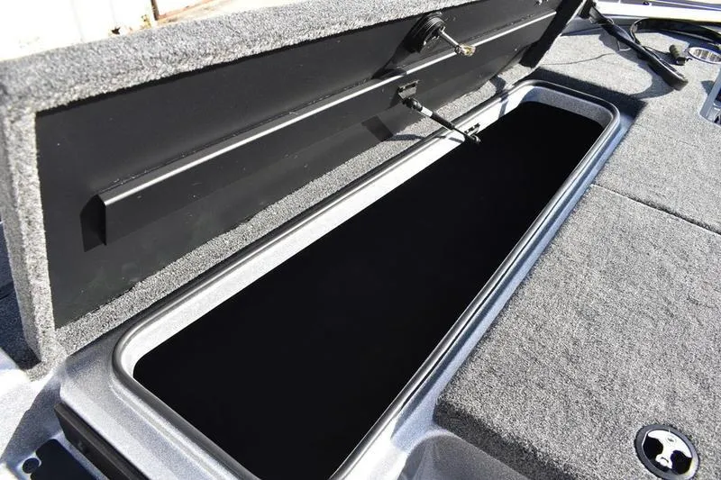Slide: The Image of Open storage compartment on 2026 Triton 179 TrX boat, featuring carpeted interior. - 7