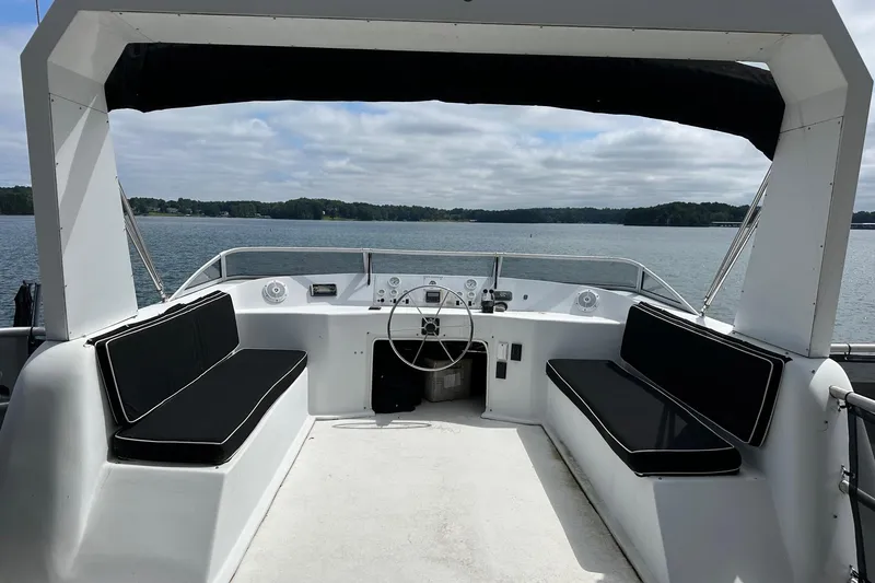 Slide: The Image of Helm of 2000 Sharpe 16x90 houseboat with black seating, overlooking serene lake. - 15