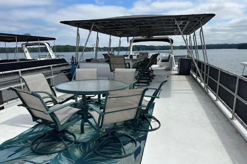 Slide: The Image of Upper deck of 2000 Sharpe 16x90 houseboat with seating and canopy on a lake. - 16