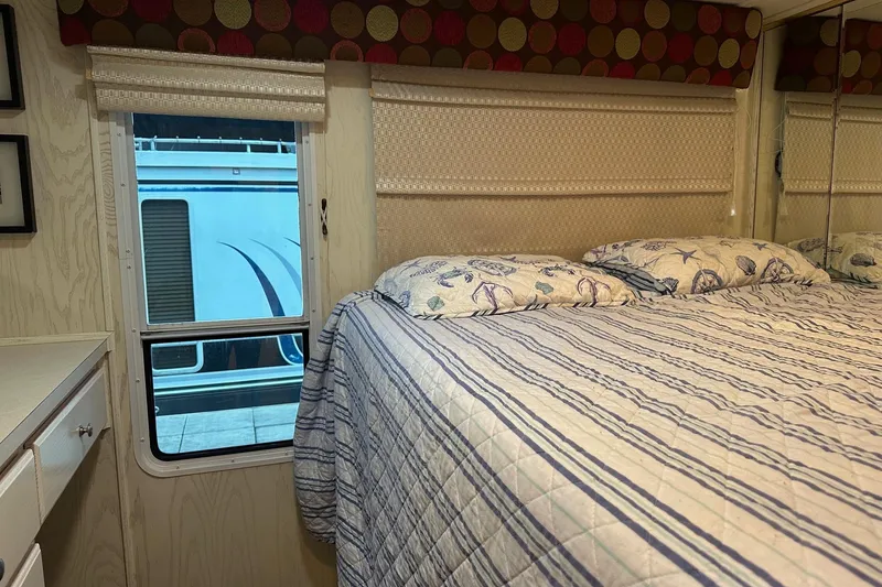 Slide: The Image of Interior of 2000 Sharpe 16x90 houseboat bedroom with striped bedding and window view. - 6