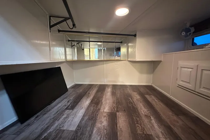 Slide: The Image of Empty room with wood flooring, mirrors, and a mounted TV in a 2000 Sharpe 16x90 model. - 9