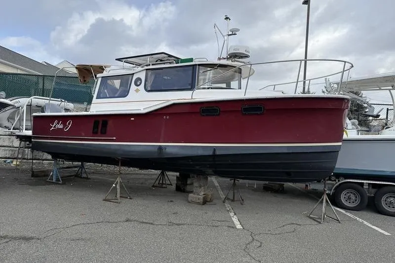 Slide: The Image of 2021 Ranger Tugs R-27 boat on stands in a parking lot. - 1