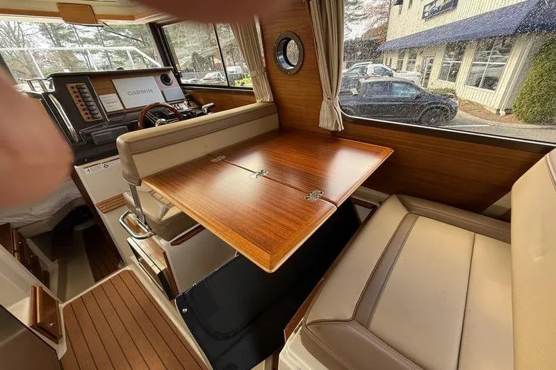 Slide: The Image of Interior of 2021 Ranger Tugs R-27 with wooden table and beige seating. - 18