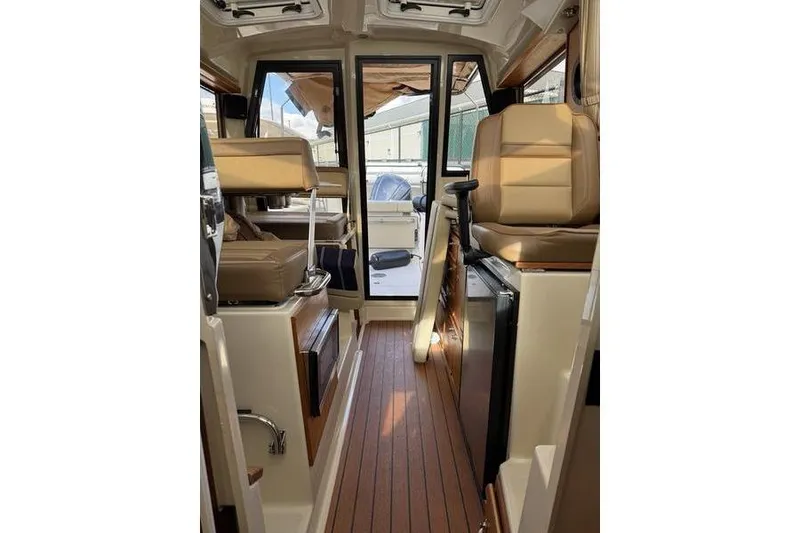 Slide: The Image of 2021 Ranger Tugs R-27 interior with seating, wood flooring, and modern amenities. - 19