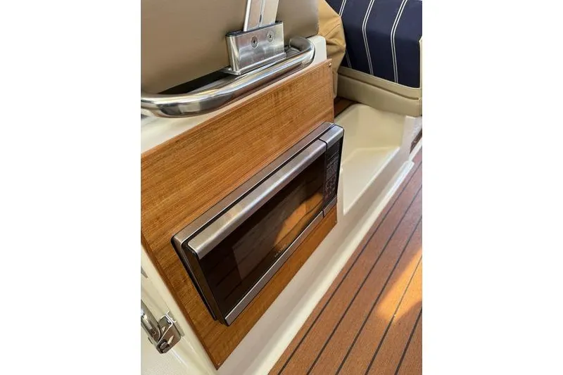 Slide: The Image of 2021 Ranger Tugs R-27 interior with built-in microwave and wood paneling. - 24