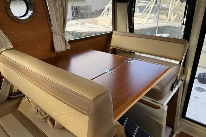 Slide: The Image of Interior of 2021 Ranger Tugs R-27 with wooden table and beige seating. - 25