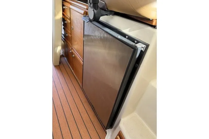 Slide: The Image of 2021 Ranger Tugs R-27 interior with wooden cabinetry and stainless steel fridge. - 27