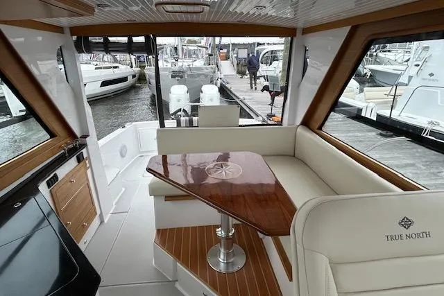 Slide: The Image of 2024 True North 34 Outboard Express interior with elegant seating and wooden table. - 14